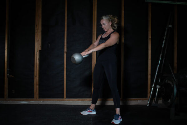 How to begin lifting weights. Kathryn Alexander of Alexander Training swings a kettlebell in her garage gym.